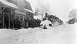 Snödränkt persontåg, draget av dubbla ånglok ankommer till stationen.