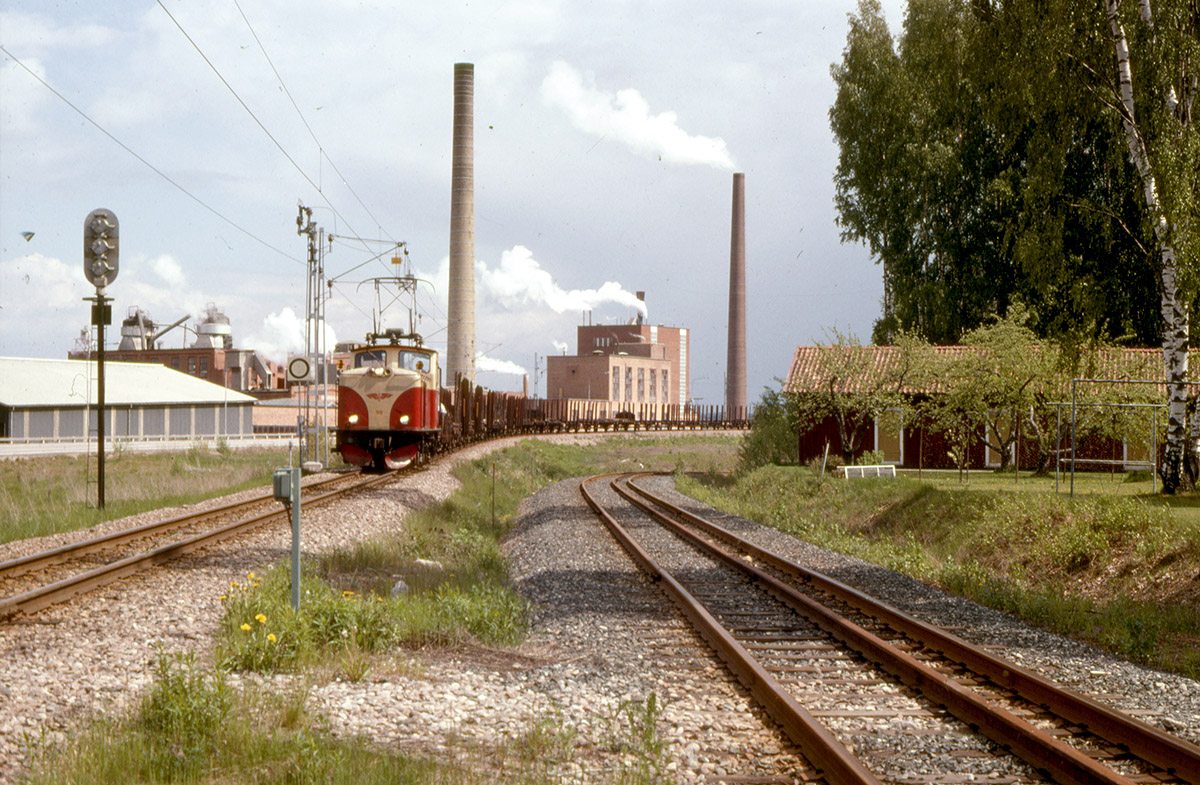 En kvalmig junidag 1976 har NKlJ lok 101 ”Hagfors” fått stopp vid infartssignalen till Deje med ett tåg innehållande 70 tomma timmervagnar på väg från Skoghall till lastningsplatsen i Musjöheden