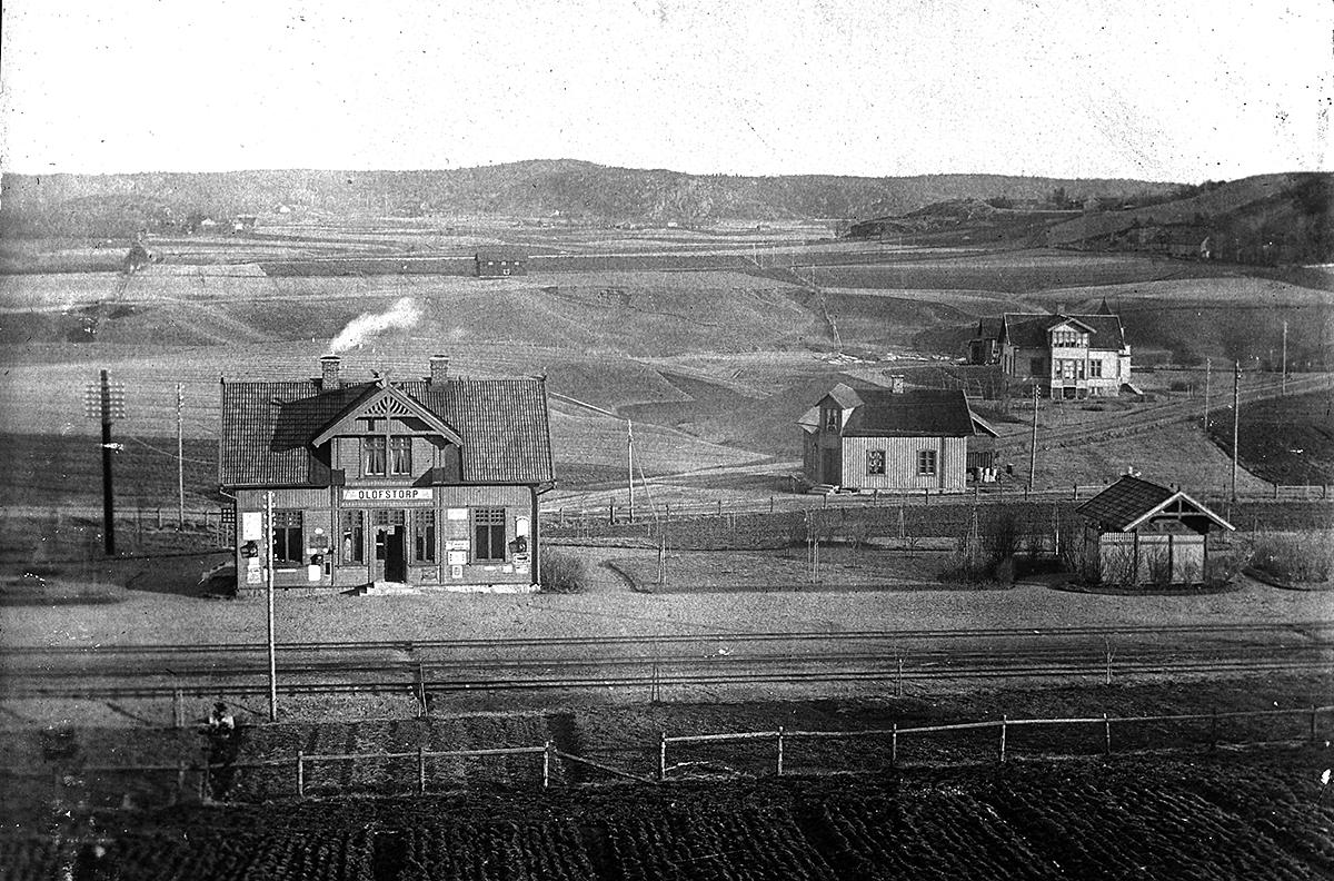 Olofstorp. Utblick ver landskapet med jrnvgsstationen i frgrunden. Jrnvgsspr med odling i frgrunden