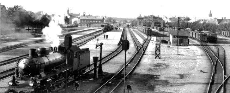 Gävle Södra i början av 1930-talet. Ett OKB-tåg, draget av en OKB E-maskin, har just kommit in från Söderhamn. I förgrunden står en av UGJ:s Bb-maskiner beredd att ersätta E-maskinen som dragkraft inför tågets fortsatta resa mot Uppsala och Stockholm.