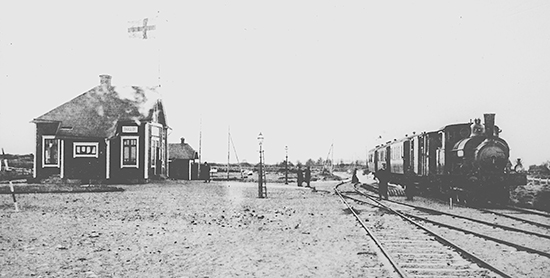 Träslöv station, troligen 1912. Lok nummer 3 med persontåg gör uppehåll. Det är kallt ute, marken är lätt snötäckt. Ångvärmen i personvagnarna är igång och utloppsångan syns längs vagnarnas underdelar. Tåget är på väg mot Ätran. Foto: KDAJ06481, Järnvägsmuseet.